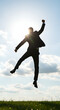 © Joa - Against the bright sky, the silhouette of a businessman in a sunlit suit leaps high into the air.