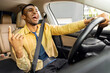 © Home-stock - Emotional black guy having fun while driving car, listening to music and singing, moving his hand, shot from inside