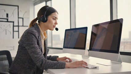 Poster - A woman sits at a computer wearing a headset, focused on her work