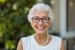 © Damir - Elderly woman with white curly hair, glasses, and pearl necklace smiling warmly outdoors. Greenery in the background. Concept of happiness and positivity. Ai generative