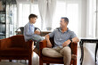 © fizkes - Young loving dad and little 8s son engage in meaningful conversation on leisure in living room, smiling, enjoy pleasant talk seated on armchairs. Parent provide wisdom or advice, trustworthy dialogue