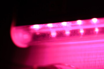 Poster - Close-up shot of a pink light illuminating a dark room, suggesting warmth and comfort.
