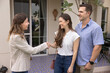 © fizkes - Happy spouses finalize house hunting, make decision, buy house shaking hands with professional real-estate agent standing in modern countryside house porch, finish meeting, feel satisfaction with deal