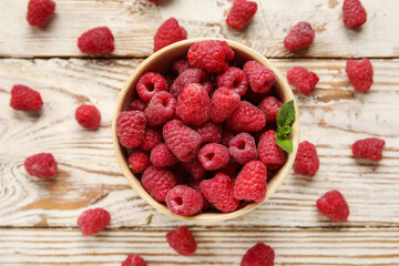 Wall Mural - Bowl with fresh raspberry on light wooden background, closeup