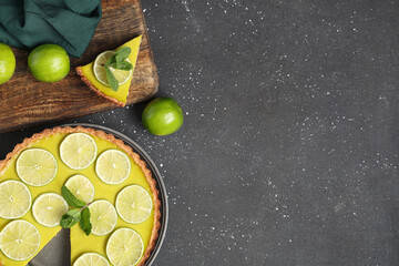 Wall Mural - plate and wooden board with tasty lime tart on black background