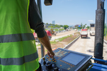 Fototapete - View from asphalt paver, showing worker controlling machinery with control panel on highway construction site