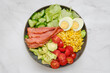 © boomeart - Fresh salad bowl with smoked salmon, vegetables, and boiled eggs served on a marble countertop