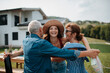 © Halfpoint - Smiling young woman receiving a gift during outdoor family gathering.
