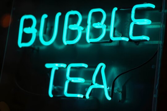 Light green neon text bubble tea at shopping window.