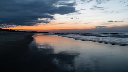 Wall Mural - serene beach sunset with calm waves and reflective sand at dusk