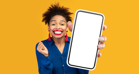 Poster - Mobile Offer. Joyful Black Lady Showing Big Smartphone With Empty Screen Advertising Great Application For Cellphone Posing Over Yellow Studio Background. New App Advertisement. Mockup, Panorama
