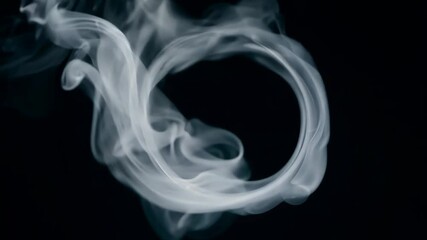 Poster - A white ring is suspended in the air, surrounded by a cloud of smoke. The smoke is a mixture of white and black particles, creating a hazy and ethereal atmosphere