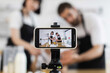 © sofiko14 - Caucasian family blogging cooking lesson using tripod-mounted smartphone. Adults assist child making dough in glass bowl
