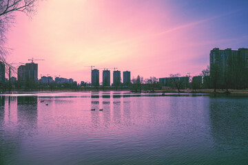 Wall Mural - Skyline, Kyiv city in the evening. Left bank of the Dnieper River. Lake Telbin at sunset. Beautiful reflection of buildings in the lake