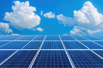 Solar panel array under bright blue sky and clouds