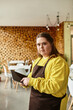 © Bliss - Confident young woman with Down syndrome engages with customers in a vibrant cafe atmosphere