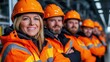 © Marina Varnava - Group of factory workers in safety gear posing proudly in front of assembly line at industrial facility