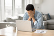 © fizkes - Man covers his face with hands while sitting at desk in front of laptop, got awful news, experiencing problems with device or internet connection, looking overworked, feels hopeless, tight deadlines