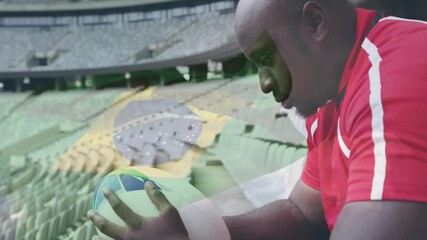 Poster - Holding soccer ball, man in red jersey with stadium seats background