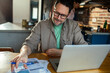 © Marko Geber - Stressed man managing finances and bills at home on laptop