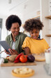 © Dorde - Playful African Mother and Daughter Cooking Together in a Bright Home Kitchen