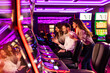 © Dragana Gordic - Group of Friends Enjoying Slot Machines in a Neon Casino Environment