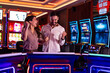 © Dragana Gordic - Excited Couple Celebrating Victory at a Casino With Slot Machines
