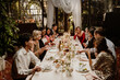 © Drobot Dean - A diverse group of adult friends, including a bride and groom, enjoy an elegant wedding reception dinner indoors. Men and women of Asian, Black, and White ethnicity are smiling and celebrating.