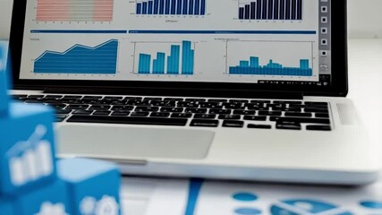 Poster - A close up of blue blocks with white icons stacked near a laptop and documents on a white surface