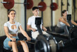 © JackF - Workout girl cross training exercising cardio using rowing machine with group of people in crossfit club