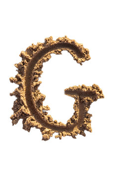 Alphabet (G) letters handwritten in sand on beach