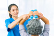© ArLawKa - Elderly woman receives medical services from home care nurse while performing muscle strengthening exercises.