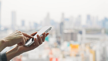 Poster - 都市を背景にスマホを使う女性