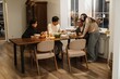 © Drobot Dean - A happy Asian family of four shares a meal at a wooden dining table. The parents and a grandson engage in conversation with an elderly grandfather while eating from a variety of dishes and drinks.