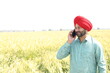 © GAJENDRRA BHATI  - Punjabi sikh farmer talking on mobile phone at wheat agriculture field. Young punjab man, People of India, Wireless technology, Copy space.
