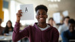 © Karina Korytchenko - Student celebrates academic achievement with proud smile while holding an A grade paper in classroom setting