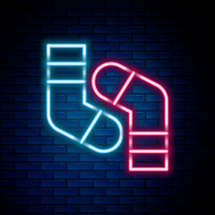 Poster - Glowing neon line Socks icon isolated on brick wall background. Colorful outline concept. Vector