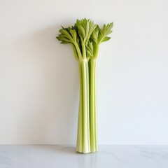 Poster - Fresh Celery Stalk with Crisp Green Ribs on White Surface - Close-up of Healthy Vegetable with Vibrant Leaves