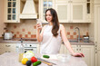 © kazakova0684 - Smiling woman using smartphone while preparing fresh vegetable salad in cozy kitchen. Healthy lifestyle, home cooking and online recipe inspiration
