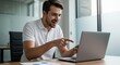 © AlfaSmart - Young adult male excitedly working at a laptop in modern office