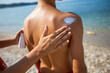 © Mediteraneo - Mother putting sunscreen on the back of her son. Sunny warm day on the beach.