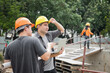 © skarie - Team of construction workers with blueprint project details in construction site. Success collaboration concept.