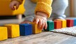 © Supanan - Capture the Joy of Childhood Toddler reaching for colorful wood blocks in sunny modern nursery, this image embodies the playful spirit of early learning Watch as a little one's curiosity leads them