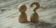 © Inspire Shots Hub - Two wooden figures stand on a wooden surface, one topped with a question mark, symbolizing uncertainty or decision-making. Simple, neutral design ideal for various concepts.