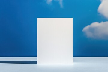 Fototapete - White box placed on a light surface with blue sky and clouds in the background