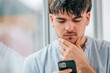© carballo - portrait of a young man or student with a mobile phone and a thoughtful expression of doubt or decision