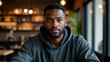 © Artem Zatsepilin - young african american man in casual grey hoodie sitting in cozy cafe. urban dining, candid portrait. leisure, solitude, modern lifestyle