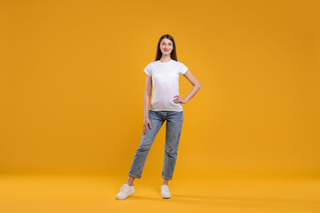 Wall Mural - woman wearing blank white t-shirt on orange background. mockup for design