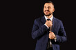 © Pixel-Shot - Young businessman straightening his tie on black background