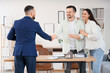 © Pixel-Shot - Male real estate agent and young pregnant couple with key from house shaking hands in office